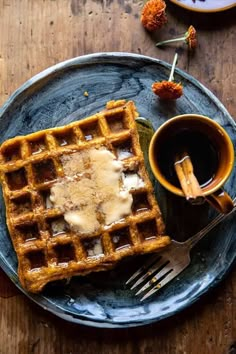 waffles with butter and syrup on a plate next to a cup of coffee