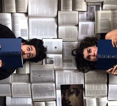 two women are laying down with books on the floor