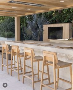 an outdoor kitchen with bar stools and television