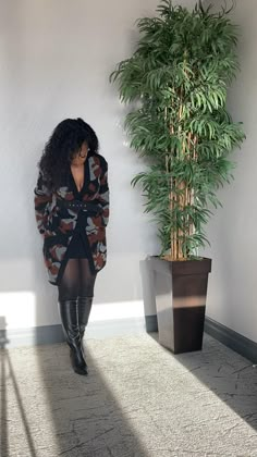 a woman standing in front of a potted plant