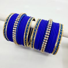 Bangle set comes with 2 sets - 1 per arm. Step into a realm of regal charm with our stunning royal blue bangles, accompanied by a captivating centre thread bangle adorned with diamond zircon stones. The deep and lustrous royal blue hue exudes a sense of grandeur and sophistication, making a bold statement wherever you go. The centre thread bangle adds a touch of artistry and delicacy, beautifully enhanced by the glistening diamond zircon stones, which add a mesmerizing sparkle to the ensemble. E Blue Traditional Bangle For Festive Occasions, Blue Bangle For Weddings And Festivals, Traditional Blue Bracelets For Festivals, Traditional Blue Bangle For Weddings, Blue Wedding Bangle For Festive Occasions, Traditional Blue Wedding Bangle, Festive Blue Round Bangle, Blue Festive Wedding Bangle, Festive Blue Wedding Bangle