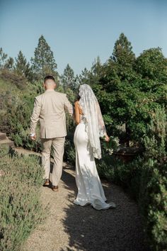 a bride and groom walking down a path