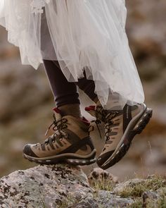 a person wearing hiking shoes standing on top of a rock