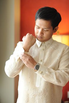 a man in a white shirt adjusting his watch