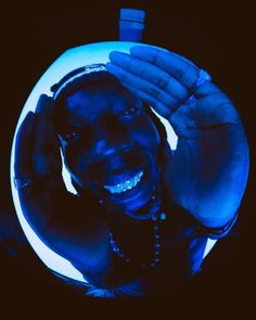 a man is smiling and holding his hands up in the air with blue light shining on him