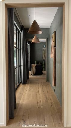 an open door leading to a hallway with wood floors and curtains on the windowsill