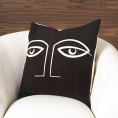 a black and white pillow with an eye drawn on the front, sitting on a chair