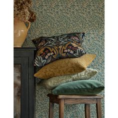 four pillows stacked on top of each other in front of a wallpapered room