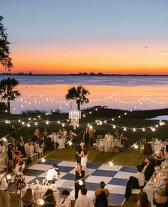 an outdoor wedding reception with lights and checkerboard dancefloors at sunset