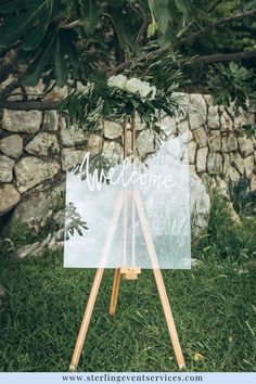 an easel with a welcome sign on it sitting in front of a stone wall