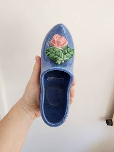 a hand holding a blue shoe with a rose painted on it