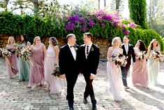 a bride and groom walking with their bridal party