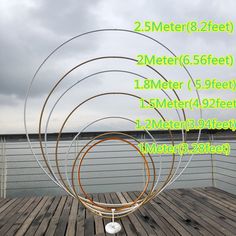 four metal circles sitting on top of a wooden deck next to water and clouds in the sky