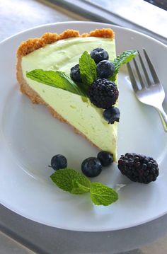 a slice of cheesecake on a plate with blueberries and mint garnish