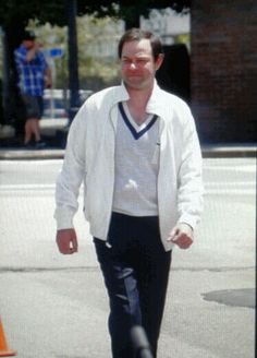 a man is walking down the street with his foot in the air and wearing black pants