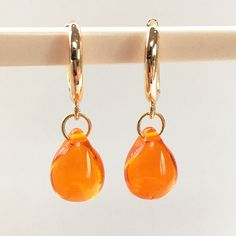 Stunning bright orange Czech glass is featured in these classic drop earrings. with quality gold huggie hoop fittings. The summery colour is simply gorgeous and stands out when you wear them. The light shines through these  transparent glossy drops.   Want this style in other colours? - https://etsy.me/3Dylcpd  - just ask Other orange earrings in this shop - https://rb.gy/kmr026 The teardrop is a popular shape and so is perfect for gifting to ladies you know-  sister, friend, wife, as well as fo Gold Teardrop Earrings, Huggie Earrings Gold, Glass Drop Earrings, Orange Earrings, Hoop Earrings Gold, Classic Earrings, Earrings Dainty, Classic Jewelry, Huggie Hoop Earrings