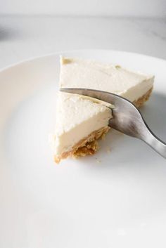 a piece of cheesecake on a white plate with a fork in the foreground