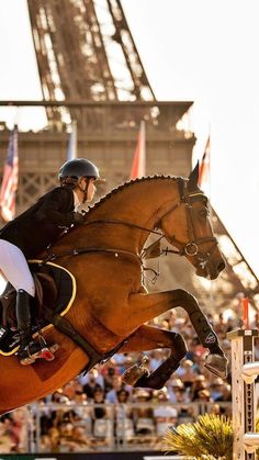 a person riding on the back of a brown horse in front of an eiffel tower