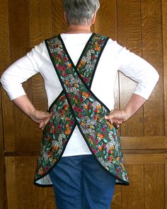 an older woman standing in front of a wooden wall with her back to the camera