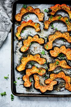 an overhead view of some cooked vegetables on a baking sheet with herbs and seasonings