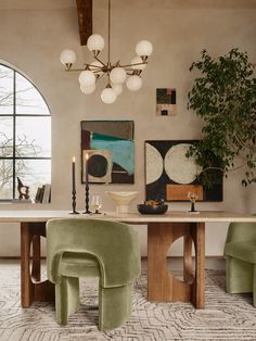 an elegant dining room with green chairs and art on the wall, along with large windows