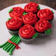 cupcakes with red frosting and green stems on a plate