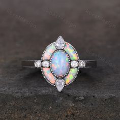 This is a beautiful Antique White Opal Engagement Ring Sterling Silver Opal Halo Engagement Ring Vintage Oval cut Ring Cocktail Ring October Birthstone Gift. --Engagement Ring-- Main Stone: 5x7mm oval cut lab created white fire opal. Side stone: Opal + Moissanite This ring is marked S925/G10K/G14K. I accept custom making order.Please contact me if you need this service. For all the jewelries,there is a 14 days money back guarantee.You can return it in the time frame without any questions.However there maybe handcrafted fee and shipping fee deducted from the original payment as it is handmade. Oval Multi-stone Opal Ring For Anniversary, Oval Opal Promise Ring With Accent Stones, Oval Opal Rings With Accent Stones, Wedding Multi-stone Oval Cabochon Rings, Oval Opal Ring With Center Stone, Oval Multi-stone Crystal Promise Ring, Oval Opal Promise Ring With Halo, Anniversary Opal Crystal Ring With Oval Shape, Oval Multi-stone Halo Ring For Anniversary