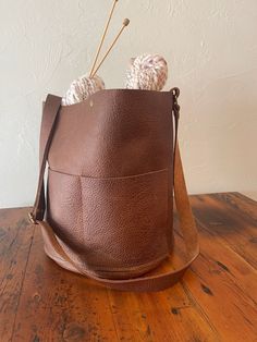 "Use this project bag to hold yarn and extras, big enough for the yarn quantity of a sweater, blanket or shawl! Fully made from US Bison leather, this large bucket bag has two exterior pockets and a small interior pocket. It is unlined, the suede side of the leather is beautiful inside! Bison leather is rustic, each bag will be slightly different since leather can vary from hide to hide. The leather will break in with the natural oils of your hands. Spot clean only. Perfect as a yarn project bag, embroidery, or any other crafting handwork. 11.5\" high x 10\" diameter, adjustable crossbody handle, 42\" at longest. We are a small company based in Manhattan, Montana. We pride ourselves on the quality of our work. Leather may have imperfections, which we see as unique characteristics! Please c On-the-go Bucket Shoulder Bag With Pockets, Everyday Bucket Bag With Pockets, Everyday Bucket Satchel With Pockets, Brown Bucket Satchel, Brown Bucket Bag For Everyday Use, Everyday Use Bucket Satchel With Pockets, Daily Use Bucket Hobo Bag With Pockets, Daily Use Hobo Bucket Bag With Pockets, Daily Use Bucket Bag With Pockets