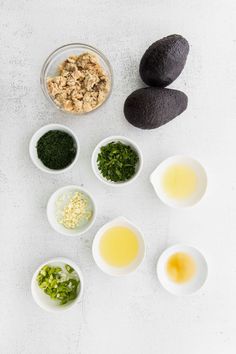 avocados, eggs, and other ingredients are arranged in bowls on a white surface