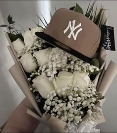 a bouquet of white roses and a yankees hat on top of each other in front of a wall