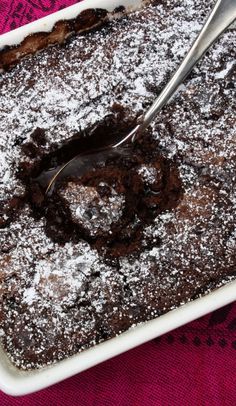 a fork is stuck into a chocolate cake with powdered sugar