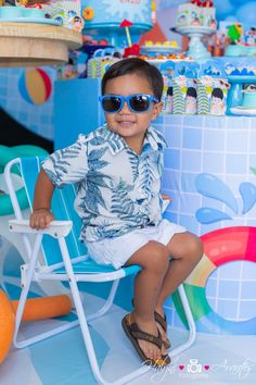 a little boy wearing sunglasses sitting in a chair