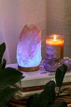 a candle sitting on top of a stack of books next to a purple crystal rock