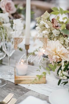 the table is set with candles, flowers and glassware for an elegant wedding reception