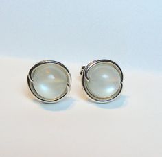 This listing is for delicate moonstone earrings.  They will be wrapped in 20 gauge sterling silver wire.   You can expect differences in the beads because no two beads are exactly the same, and the beads measure about 6mm.  They have mostly white/off-white flashing that appears depending on the angle and the light source.   The wire I use is solid Argentium sterling silver.  Argentium sterling silver is more pure than traditional sterling silver (935 vs 925).  Argentium is brighter, stronger, mo White Moonstone Wire Wrapped Earrings, Moonstone Earrings, Silver Wire, Jewelry Earrings Studs, Moonstone, Gemstone Rings, Jewelry Earrings, Stud Earrings, Accessory Gift