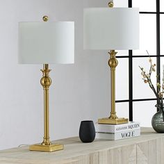 two lamps sitting on top of a wooden table next to a vase with flowers in it