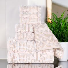 a stack of towels sitting next to a potted plant