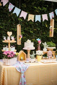 a table topped with cakes and desserts next to a green wall covered in greenery