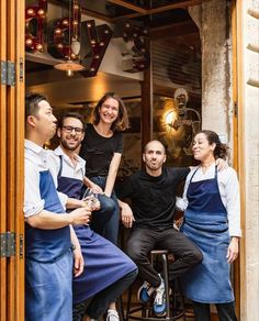 a group of people standing around each other in front of a restaurant door with their arms around one another