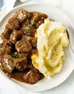 a white plate topped with meat and mashed potatoes