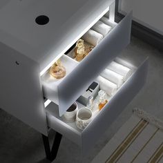 an open drawer in the middle of a white cabinet with bottles and other items inside