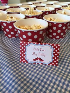 red and white polka dot paper cups with popcorn in them on a blue table cloth