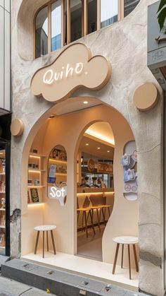 the outside of a store with two stools in front of it and an arched window