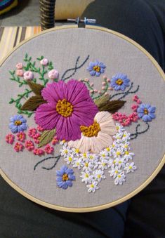 a close up of a person holding an embroidered object with flowers on it and in front of them