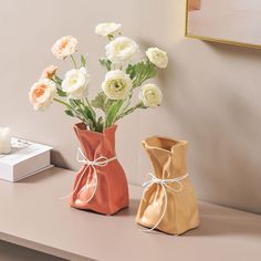 two vases that have flowers in them on a table