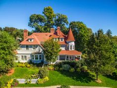 an aerial view of a large house surrounded by trees and shrubs with a red roof