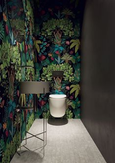 a toilet and sink in a room with wallpapered plants on the walls behind it