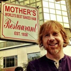 a man standing in front of a sign for a restaurant that says mother's world's best baked ham