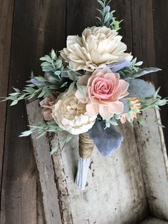 a bridal bouquet with pink and white flowers on a wooden doorknott