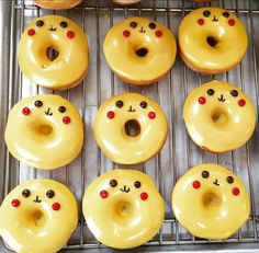 twelve donuts with yellow frosting and red noses are arranged on a cooling rack